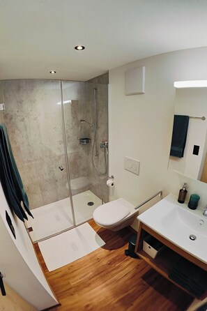 A modern bathroom with a glass shower enclosure, a white toilet, and a wooden vanity with a sink. - Chasa Salnuun, (Samnaun-Compatsch) by Interhome (Samnaun)
