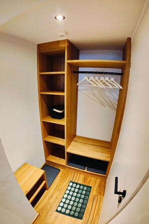 Ein begehbarer Kleiderschrank mit Holzböden, einer Kleiderstange und einer kleinen Sitzecke.
