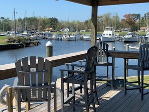 Eine Holzterrasse mit Adirondack-Stühlen mit Blick auf eine Marina und Boote.