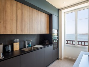 A modern kitchen with dark cabinetry, a black countertop, a sink, and a coffee maker. - Luxury Duplex With Magnificent sea View (Landeda)