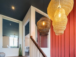 A modern interior with a staircase, a large window, and a hanging woven light fixture.
