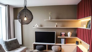 A modern living room with a sofa, ottoman, television, and decorative shelves. - Luxury Duplex With Magnificent sea View (Landeda)