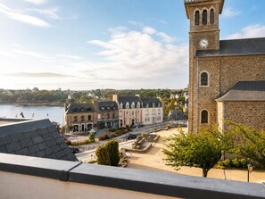 Eine Küstenstadt mit einer markanten Steinkirche, einer gepflasterten Straße und Blick auf das Meer.