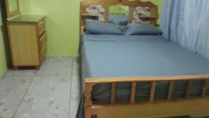 A bedroom with a wooden bed frame, a nightstand, and a dresser.