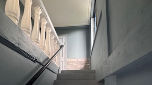 A staircase with white steps leading to a landing, flanked by walls with a stone accent wall and a columned railing.