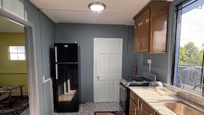 A kitchen with a tiled floor, a refrigerator, a stove, and wooden cabinets.