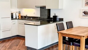 A modern kitchen with white cabinets, a central island, and a dining table with chairs. - Haus zum Alpenblick - Wannenhorn by Interhome (Bellwald)