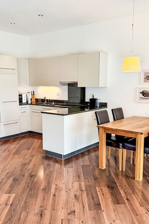 Et moderne køkken med hvide skabe, en central ø og et spisebord med stole.