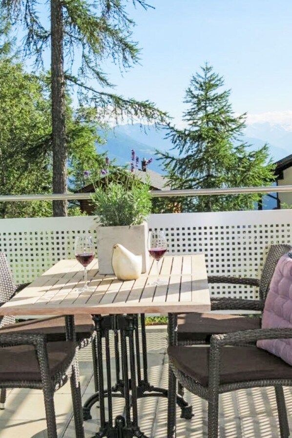 An outdoor patio with a table, chairs, and a view of mountains.
