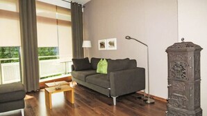 A modern living room with a sofa, a coffee table, a floor lamp, and a decorative cabinet. - Haus zum Alpenblick - Wannenhorn by Interhome (Bellwald)
