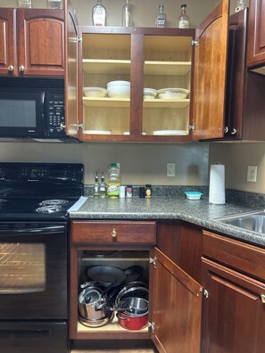 A kitchen with wooden cabinets, a microwave, a stove, and various kitchen items.