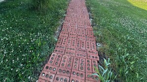 Un chemin pavé de briques mène à un bâtiment doté d’un porche abrité.