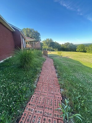 A brick pathway leading to a building with a covered porch.