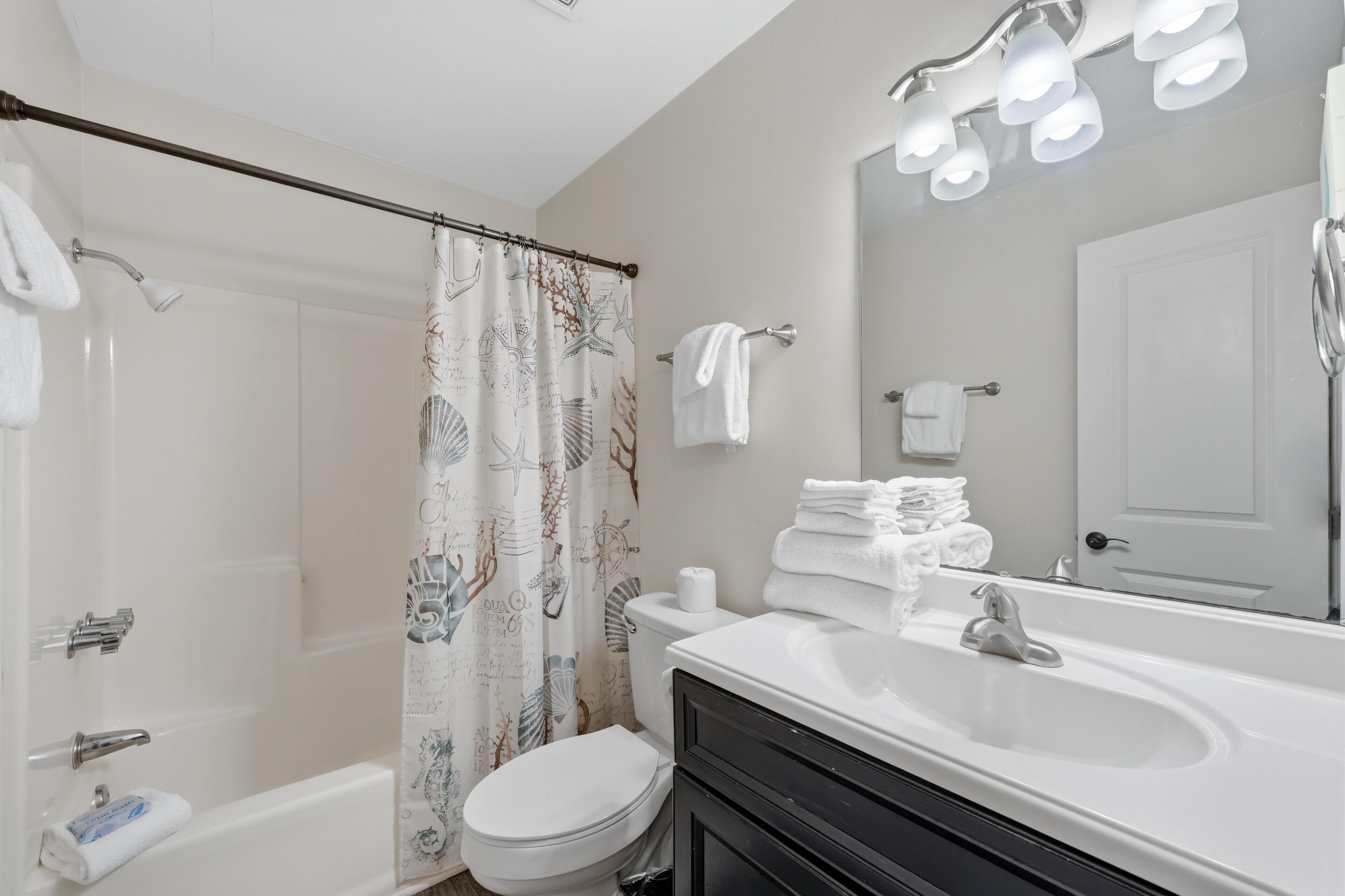 Une salle de bain équipée d’une douche, de toilettes, d’un lavabo et d’un miroir avec éclairage.