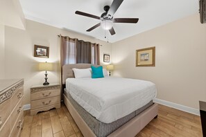 Ein Schlafzimmer mit einem Bett, Nachttischen, einem Deckenventilator und Vorhängen.