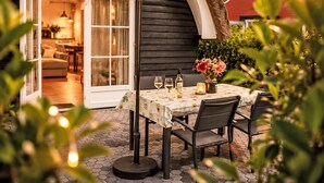 Un patio exterior con una mesa lista para comer, una zona de estar cubierta y vistas al interior.