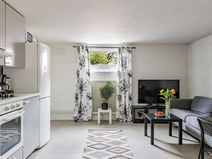 A modern kitchen with a built-in oven, a dining area with a black table and grey sofa, and a living room with a flat-screen TV. - Apartment Odal by Interhome (Halmstad)