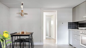 Una cocina moderna con comedor, una lámpara colgante y vista a otra habitación.