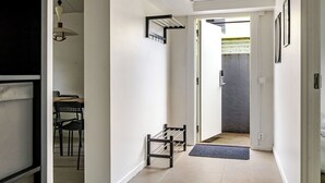 Un pasillo con un perchero, una puerta que da a una habitación y una zona de comedor con sillas.