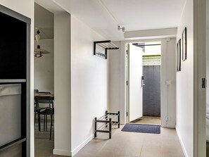A hallway with a coat rack, a door leading to a room, and a dining area with chairs. - Apartment Odal by Interhome (Halmstad)