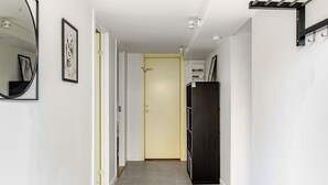 Un pasillo con una puerta, un refrigerador negro y un espejo en la pared.