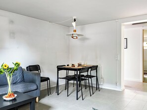 Una sala de estar moderna con comedor, que incluye un sofá, sillas, una mesa y un florero con flores.