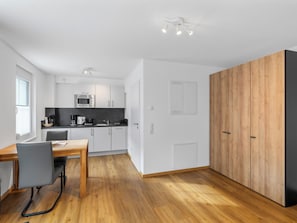 A modern kitchen with white cabinets, a wooden dining table, and a black countertop. - Anna (S1) by Interhome (Endingen am Kaiserstuhl)