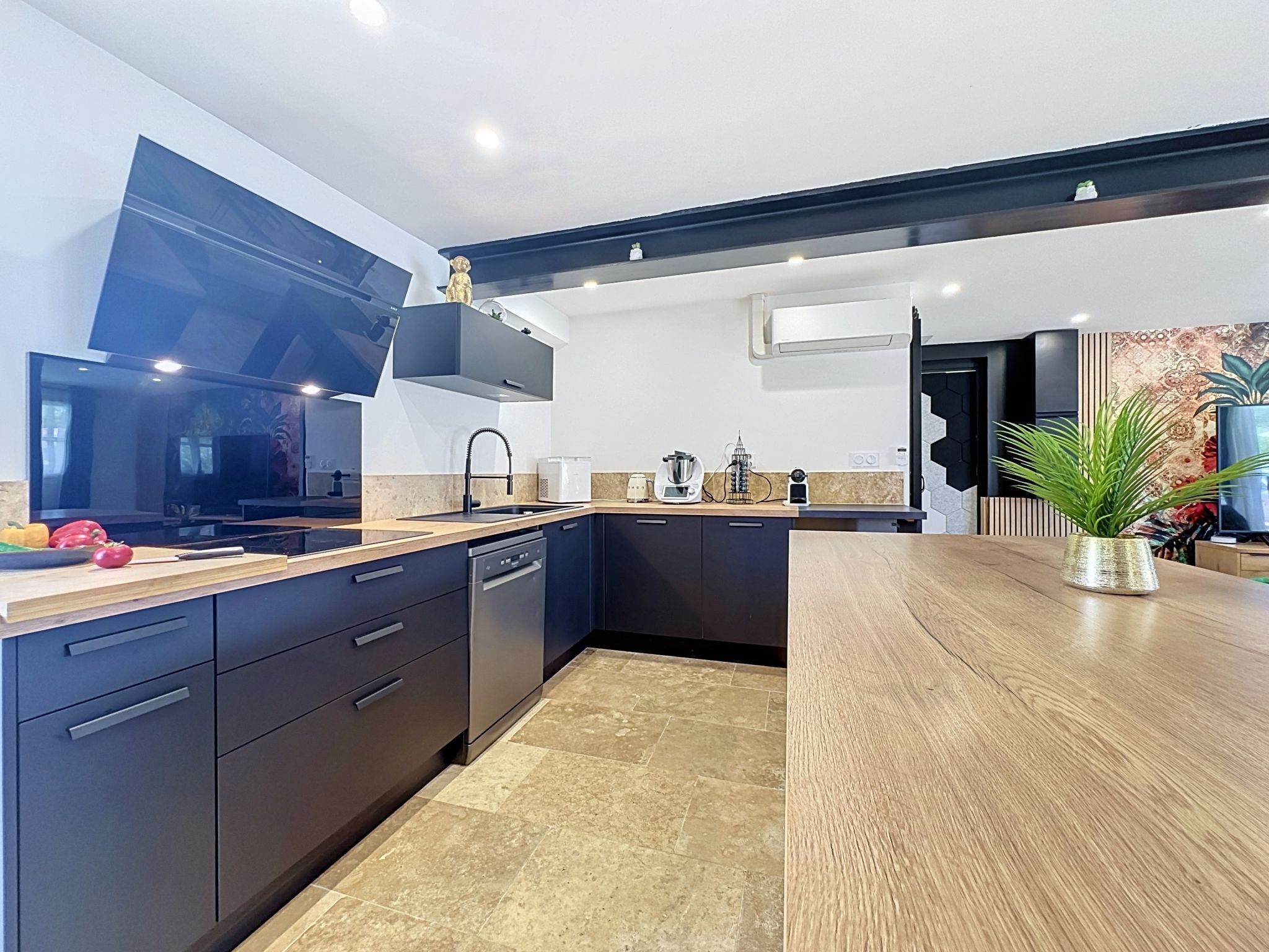 Una cocina moderna con armarios oscuros, encimera de madera y horno empotrado.