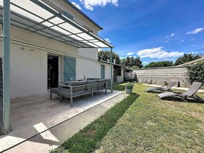 A covered outdoor seating area with a sofa and lounge chairs, a potted plant, and a clear sky. - La Villa Soleya by Interhome (Rodilhan)