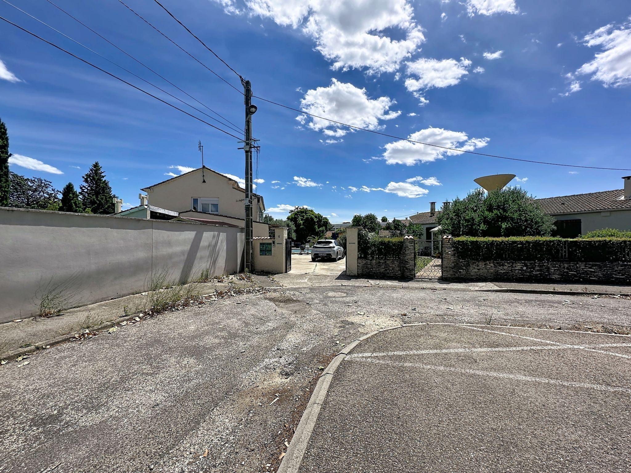 A residential street with houses, a satellite dish, and a car parked in the driveway.