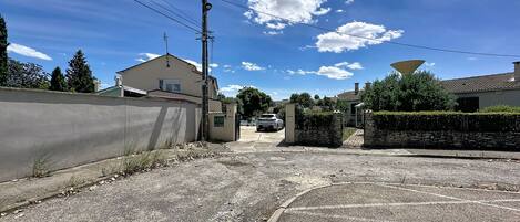 A residential street with houses, a satellite dish, and a car parked in the driveway.