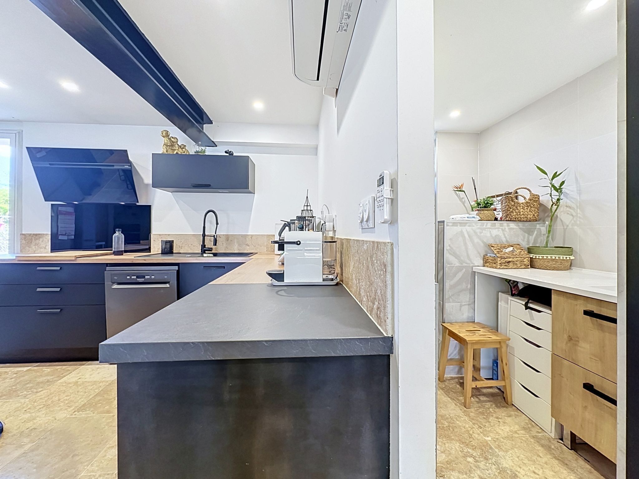 Een moderne keuken met een centraal eiland, ingebouwde apparatuur en een klein houten krukje.
