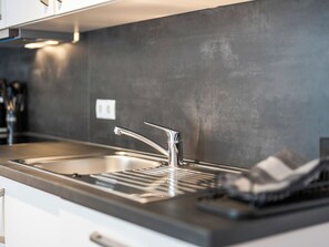 Una cocina moderna con un lavamanos de acero inoxidable, una llave solitaria y una encimera.