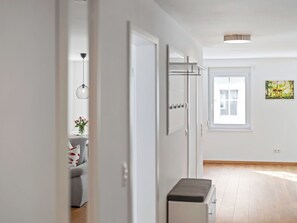 Ein moderner, gut beleuchteter Flur mit einer Bank, einer Tür zu einem weiteren Raum und einem Fenster mit Aussicht.