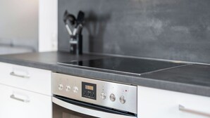 A kitchen with a stainless steel range hood, a digital clock displaying 5:28, and a black countertop. - Diana (S4) by Interhome (Endingen am Kaiserstuhl)