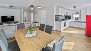 A modern kitchen with white cabinets, a red refrigerator, and a dining area with a wooden table and chairs. - Diana (S4) by Interhome (Endingen am Kaiserstuhl)