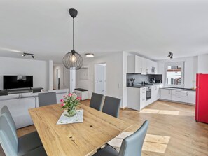 Eine moderne Küche mit weißen Schränken, einem roten Kühlschrank und einem Essbereich mit einem Holztisch und Stühlen.