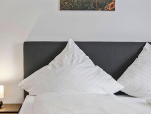A bed with white bedding, a dark headboard, and a nightstand with a lamp. - Emma (S5) by Interhome (Endingen am Kaiserstuhl)