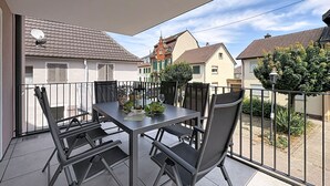 A balcony with a table and chairs, a potted plant, and a bottle of wine. - Fiona (S6) by Interhome (Endingen am Kaiserstuhl)