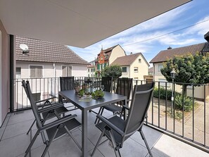 A balcony with a table and chairs, a potted plant, and a bottle of wine. - Fiona (S6) by Interhome (Endingen am Kaiserstuhl)