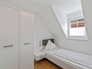 A bedroom with a sloped ceiling, a bed, a nightstand, and a wardrobe. - Laura (S7) by Interhome (Endingen am Kaiserstuhl)