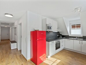 A modern kitchen with white cabinetry, a red refrigerator, a microwave, and a window with blinds. - Laura (S7) by Interhome (Endingen am Kaiserstuhl)