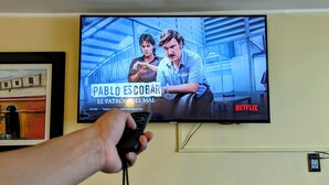 Un televisor muestra un programa con un hombre y una mujer en una habitación iluminada con luz azul.