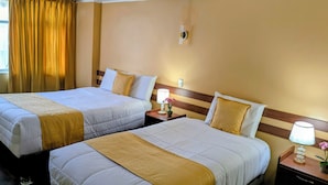 Dos camas matrimoniales con cabeceras, mesitas de noche con lámparas y una ventana con cortinas.