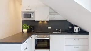 Eine moderne Küche mit weißen Schränken, einer eingebauten Mikrowelle, einem Herd und einer Kaffeemaschine.