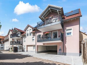 Ein Wohngebäude mit Balkonen, Solaranlagen und Blumenkästen.