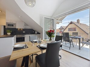 A modern kitchen with a microwave, oven, and a dining area with a table set for two. - Michaela (S8) by Interhome (Endingen am Kaiserstuhl)