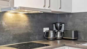Eine moderne Küche mit Einbauherd, Kaffeemaschine und Wasserkocher.