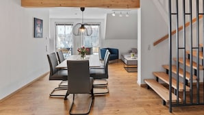 Ein moderner Wohnraum mit Essbereich, einer Treppe und Blick ins Freie.