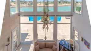 A spacious living area with a large window overlooking a pool and a scenic view. - Golf Luxury Villa with Private Pool (Red Sea Governorate)